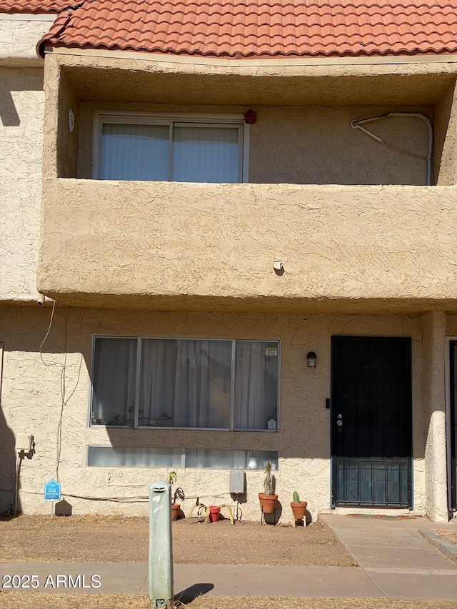 exterior space with a tiled roof, a balcony, and stucco siding