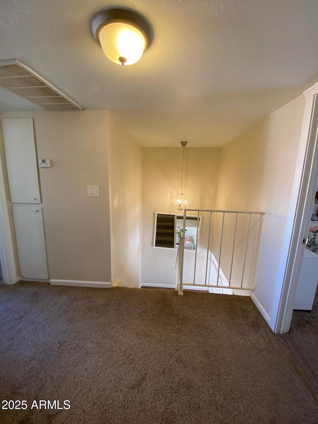 empty room with visible vents, dark carpet, and baseboards