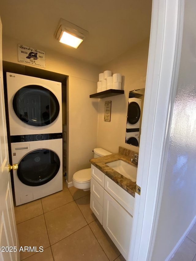 half bath with toilet, tile patterned flooring, stacked washer / dryer, and vanity