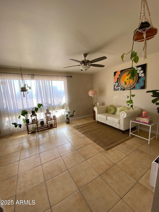 unfurnished living room featuring light tile patterned floors, ceiling fan, and baseboards