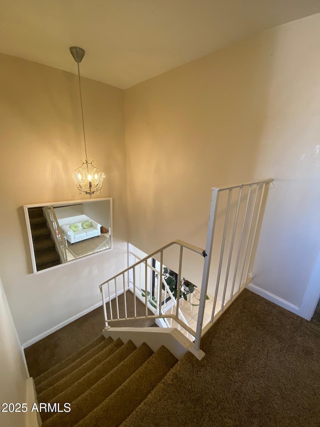 staircase featuring a chandelier, carpet floors, and baseboards