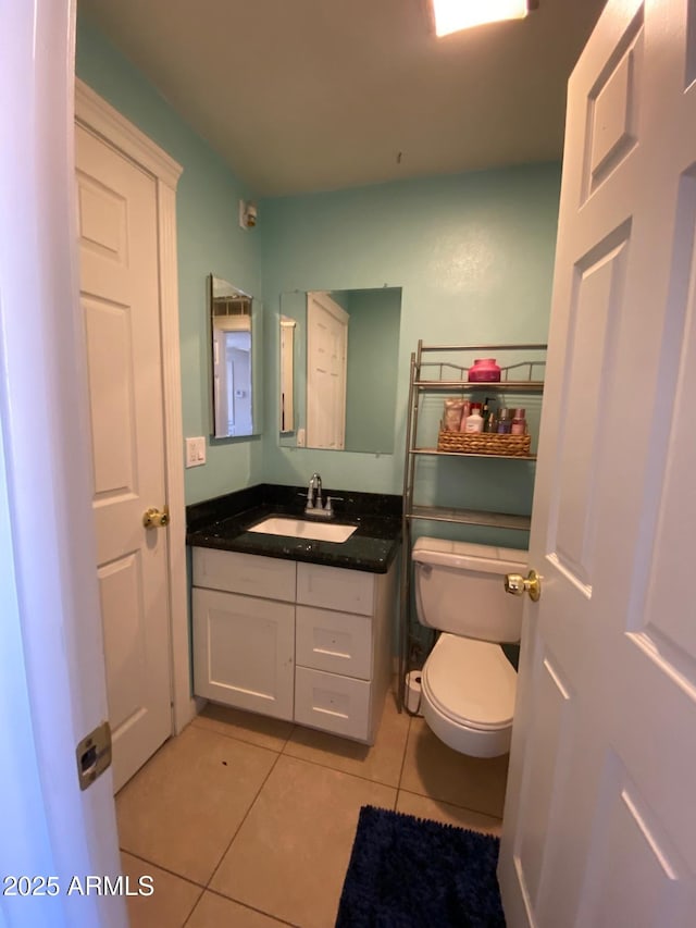 half bath with tile patterned flooring, vanity, and toilet