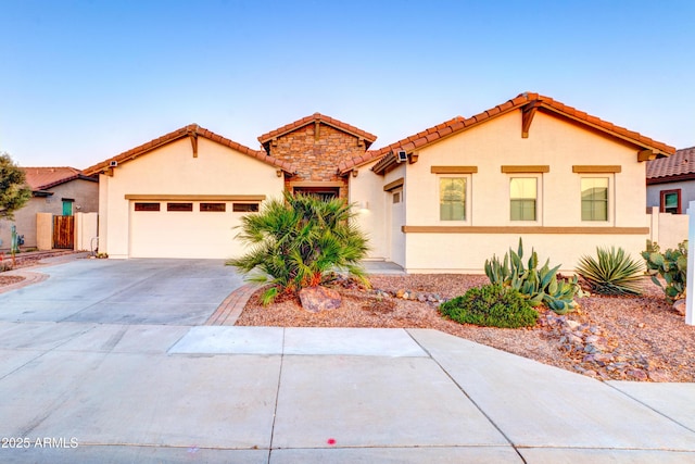 mediterranean / spanish home featuring stucco siding, driveway, a tiled roof, and an attached garage