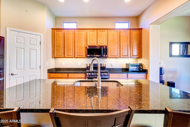 kitchen featuring dark stone countertops, recessed lighting, a center island with sink, and stainless steel appliances