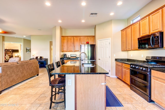 kitchen with open floor plan, a breakfast bar, dark stone counters, range with two ovens, and freestanding refrigerator