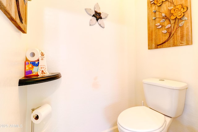 half bathroom with baseboards and toilet