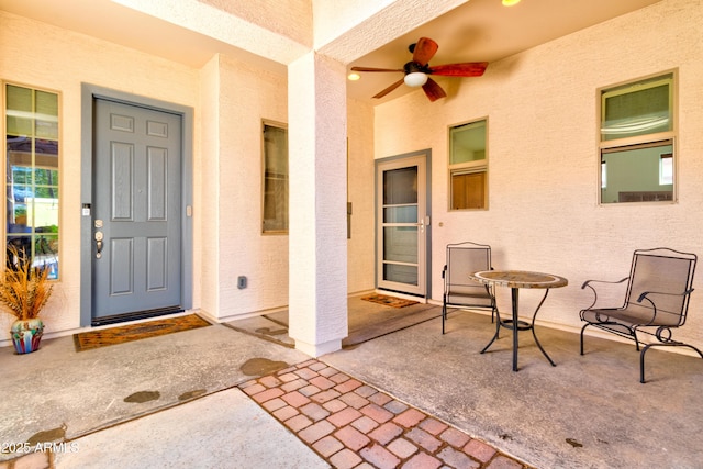 view of exterior entry with stucco siding, a patio area, and ceiling fan