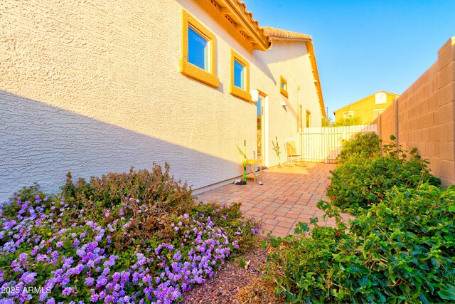 view of side of home with a patio area, stucco siding, and a fenced backyard