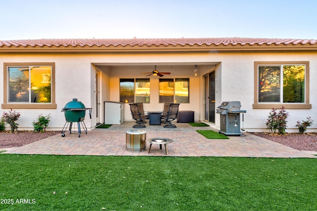 rear view of property with a patio area, stucco siding, a lawn, and ceiling fan