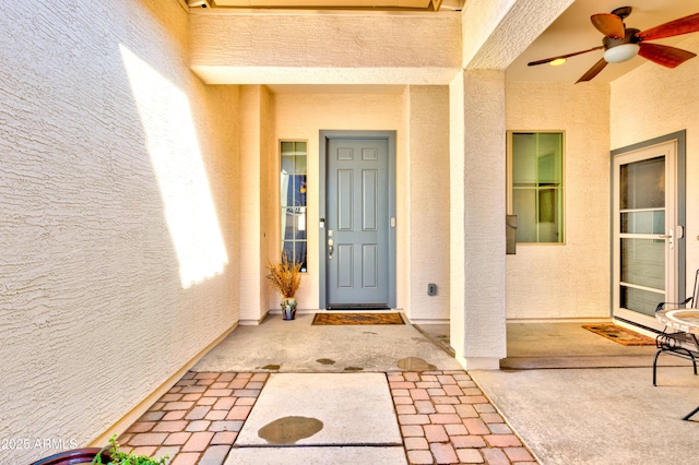 doorway to property featuring stucco siding and ceiling fan