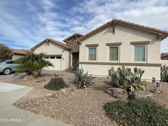 view of front facade with stucco siding, driveway, an attached garage, and a tile roof