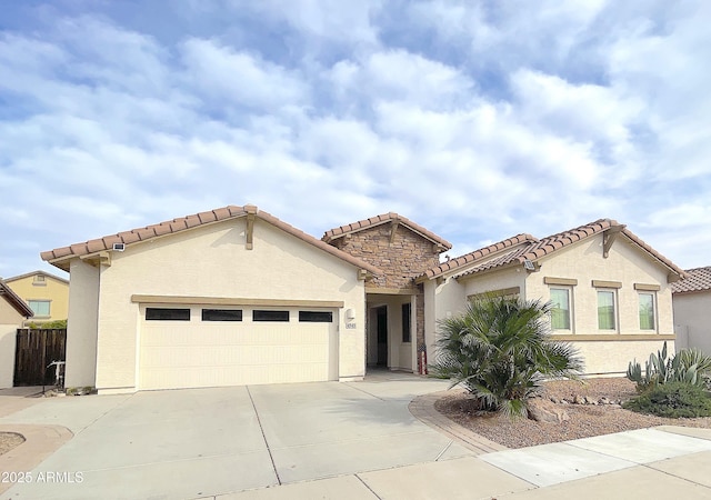 mediterranean / spanish-style home featuring a tiled roof, driveway, stucco siding, and an attached garage