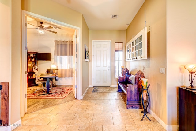 foyer entrance featuring light tile patterned floors, visible vents, baseboards, and a ceiling fan