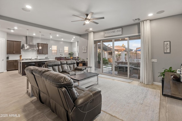 living room with sink, ceiling fan, and light hardwood / wood-style floors