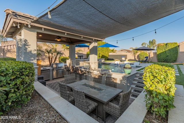 view of patio with area for grilling, ceiling fan, and a fire pit