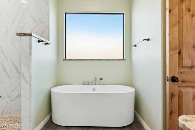 bathroom featuring a washtub, wood-type flooring, and a healthy amount of sunlight