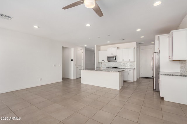 kitchen featuring a kitchen island with sink, stainless steel appliances, tasteful backsplash, and visible vents