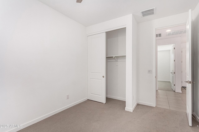 unfurnished bedroom with carpet floors, a closet, visible vents, and baseboards