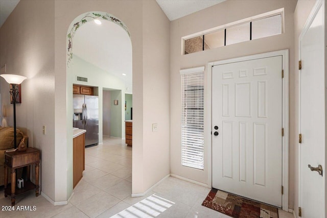 entryway with light tile patterned floors and lofted ceiling