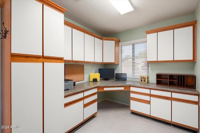 office with built in desk and a textured ceiling