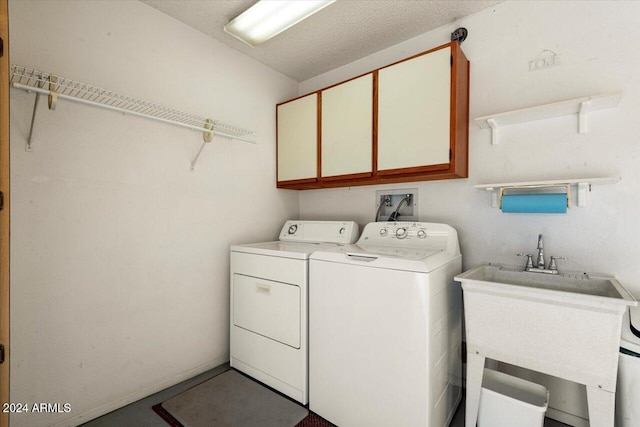 laundry area featuring sink, cabinets, a textured ceiling, and washing machine and dryer