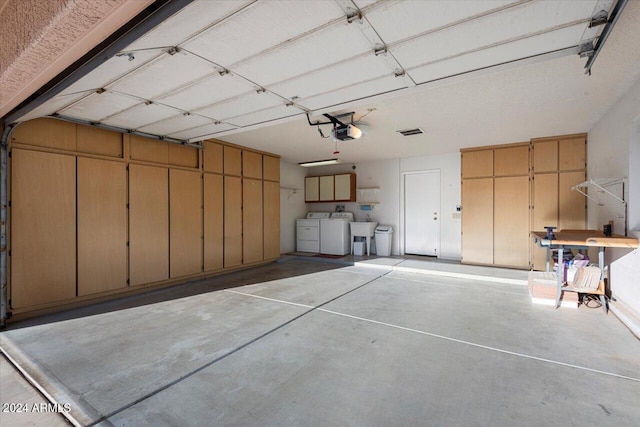 garage with washing machine and dryer, a garage door opener, and sink