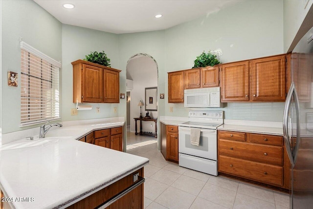 kitchen with sink, light tile patterned flooring, a high ceiling, and white appliances