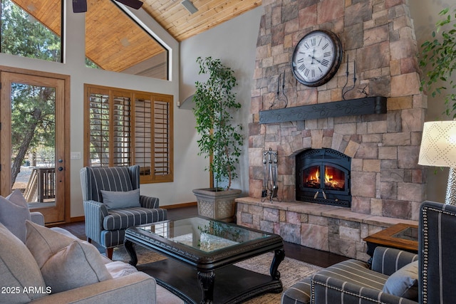 living area with baseboards, a stone fireplace, wooden ceiling, and a wealth of natural light