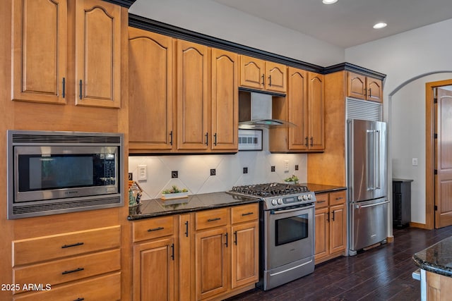 kitchen featuring dark stone counters, dark wood-type flooring, recessed lighting, under cabinet range hood, and appliances with stainless steel finishes