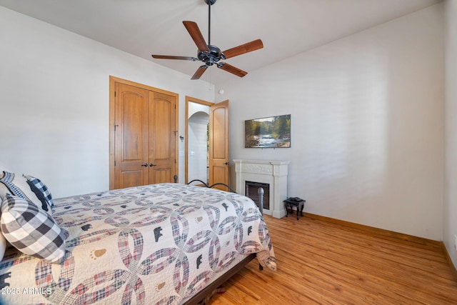 bedroom with baseboards, a closet, light wood-type flooring, and a ceiling fan