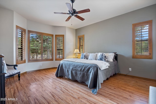 bedroom featuring a ceiling fan, light wood-style flooring, and baseboards