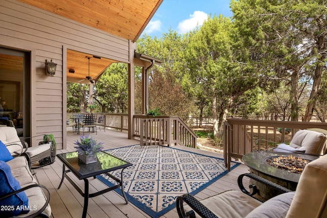 wooden deck with an outdoor living space with a fire pit, outdoor dining area, and ceiling fan