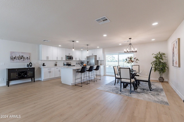 kitchen featuring pendant lighting, a center island, white cabinetry, light hardwood / wood-style flooring, and stainless steel appliances