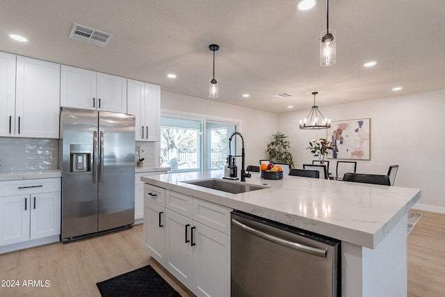 kitchen with sink, decorative light fixtures, a center island with sink, white cabinetry, and appliances with stainless steel finishes