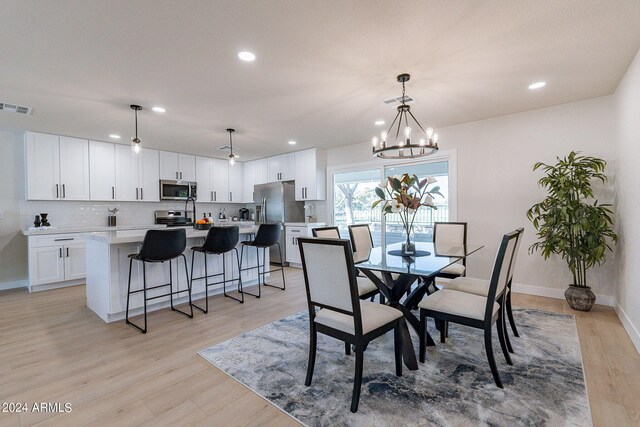 dining space featuring a notable chandelier and light wood-type flooring