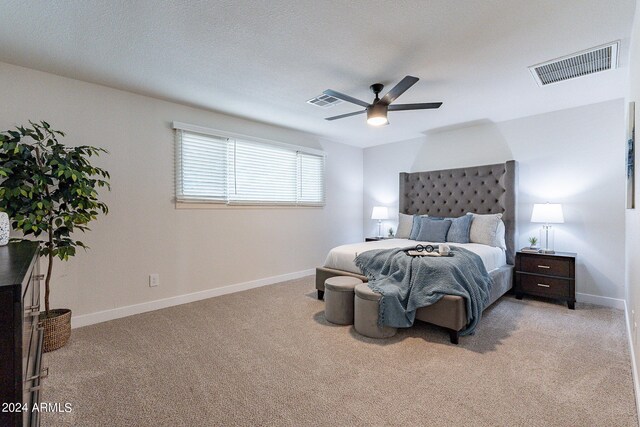 carpeted bedroom with ceiling fan and a textured ceiling