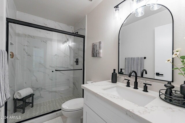 bathroom with vanity, toilet, and a shower with door