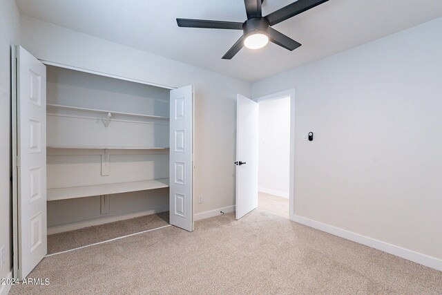 unfurnished bedroom featuring ceiling fan, light colored carpet, and a closet