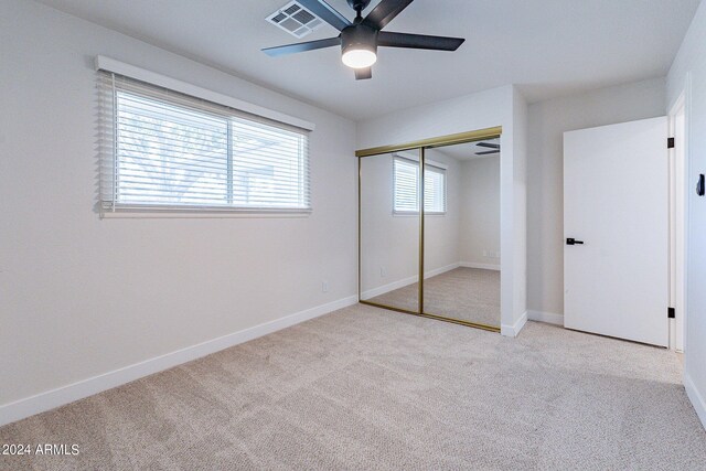 unfurnished bedroom with a closet, light colored carpet, and ceiling fan