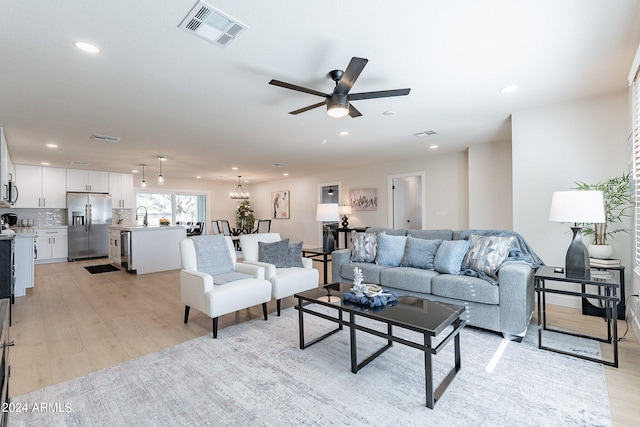 living room featuring ceiling fan, light wood-type flooring, and sink