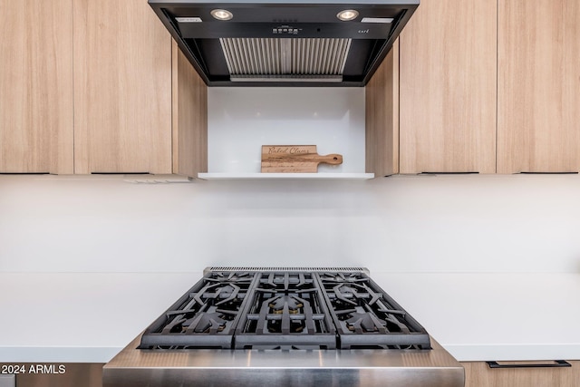 kitchen featuring light brown cabinetry, extractor fan, and stove