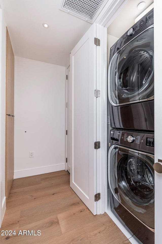 laundry room with stacked washer and dryer and light wood-type flooring