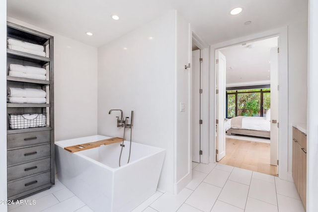 bathroom with tile patterned floors, a washtub, and vanity