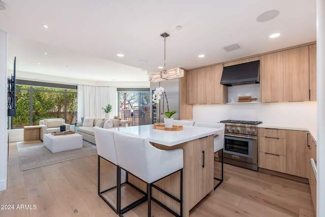 kitchen featuring a center island, light hardwood / wood-style flooring, a breakfast bar, high end range, and exhaust hood