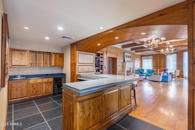 kitchen featuring a chandelier, wine cooler, a kitchen island, and sink