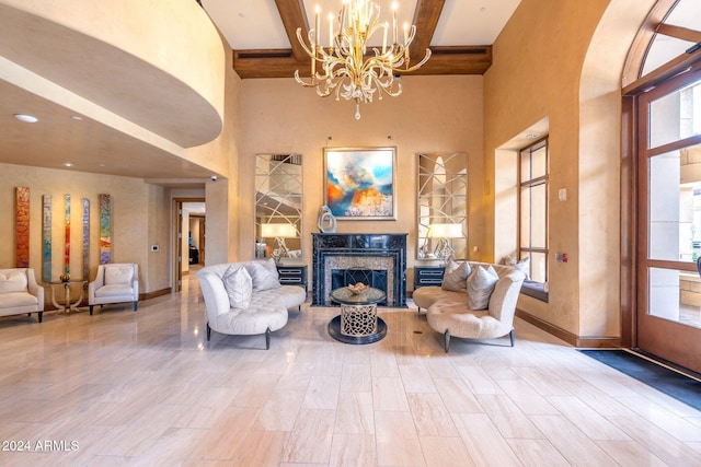 living area featuring a high end fireplace, beam ceiling, a towering ceiling, and an inviting chandelier