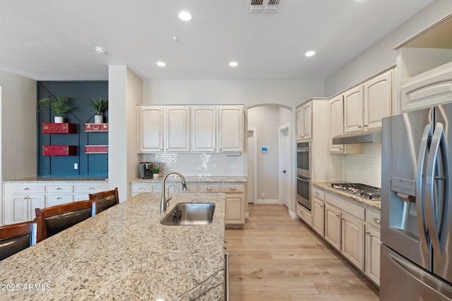 kitchen featuring light stone counters, sink, stainless steel appliances, and light wood-type flooring