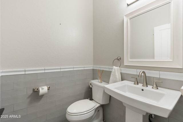 bathroom with tile walls, sink, and toilet