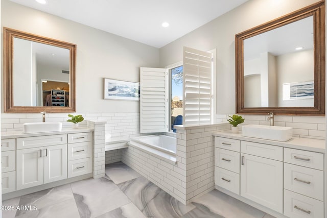 bathroom with vanity and tiled tub