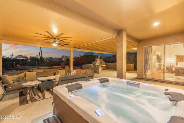 patio terrace at dusk featuring ceiling fan and a hot tub